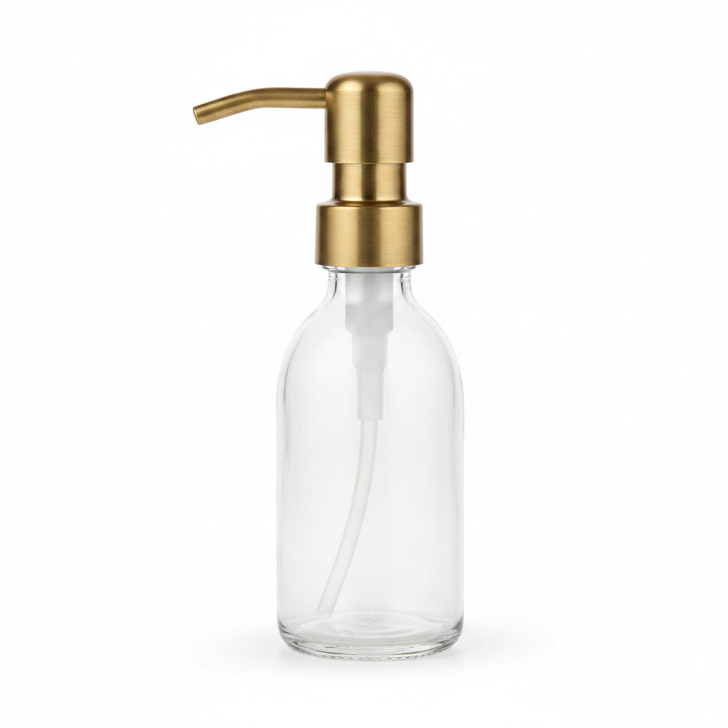 Clear glass soap dispenser with gold pump on a kitchen counter