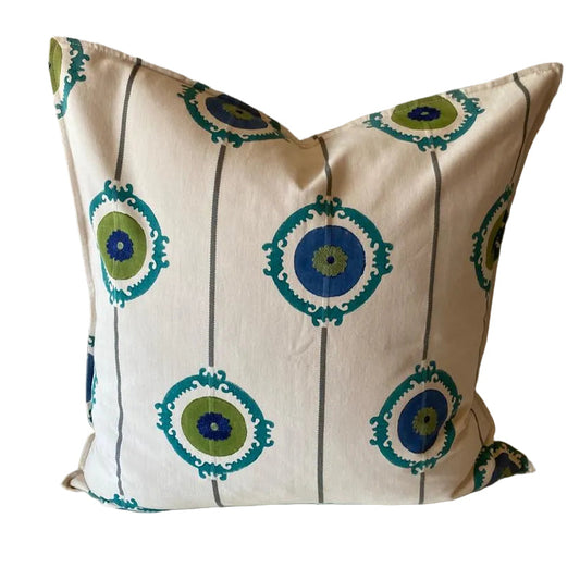 Decorative pillow with green and blue circular patterns on a beige background