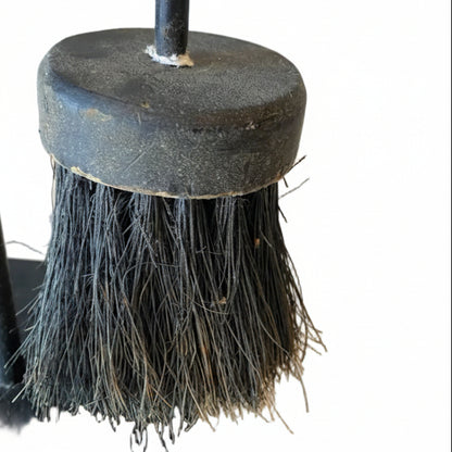 Black fireplace brush with bristles on a white surface