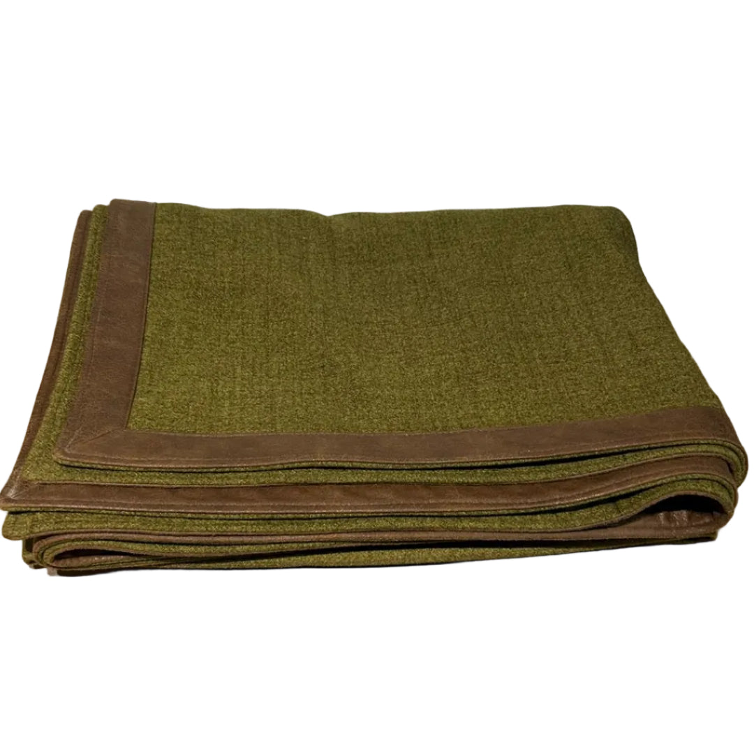 Folded green blanket with brown border on a wooden surface