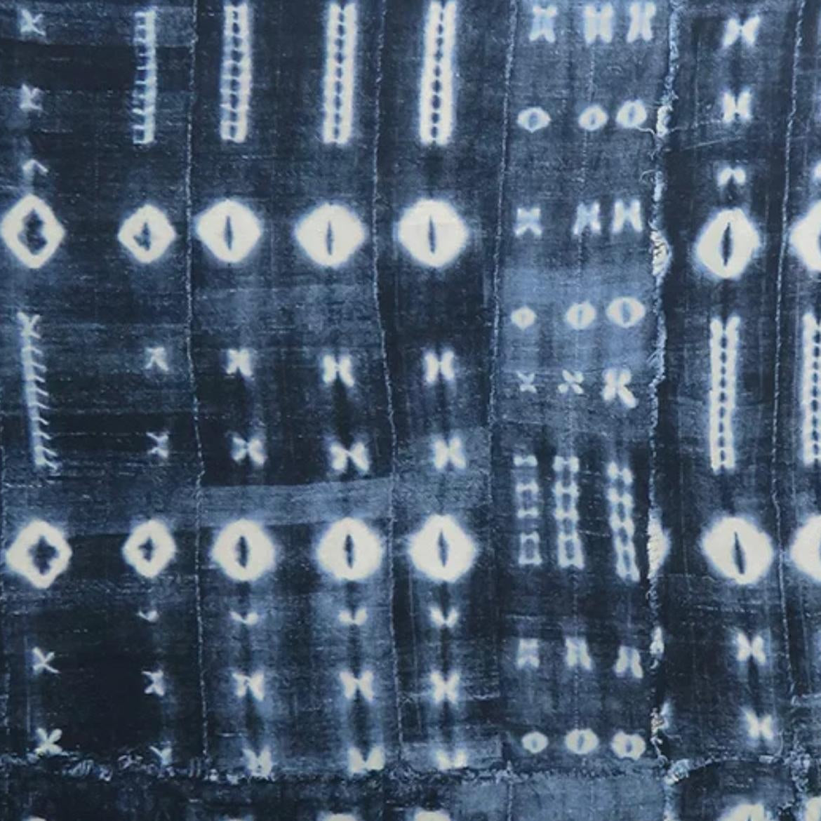 Close-up of a textured fabric with a pattern of white shapes on a dark blue background