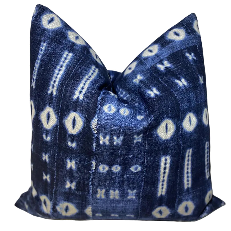 Blue and white patterned pillow on a white fabric background Indigo Mavromac 
