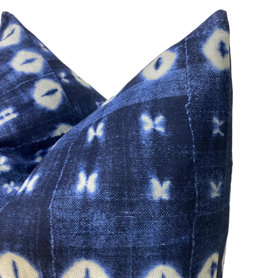 Blue patterned pillow with white accents on a neutral background