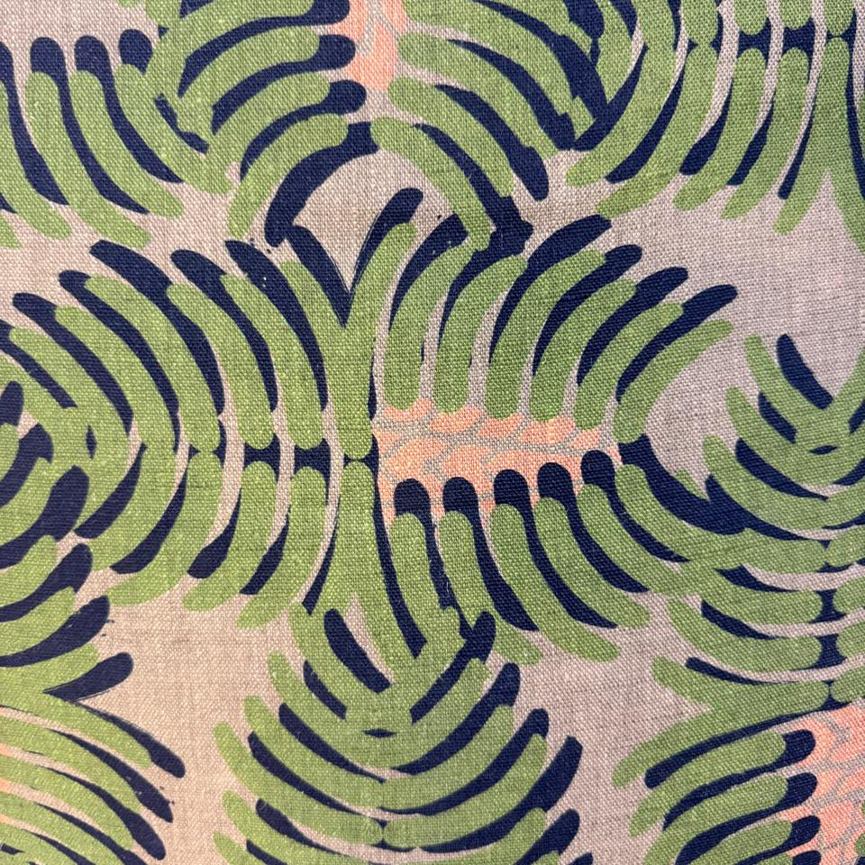 Fabric with a leaf pattern in green and navy on a beige background